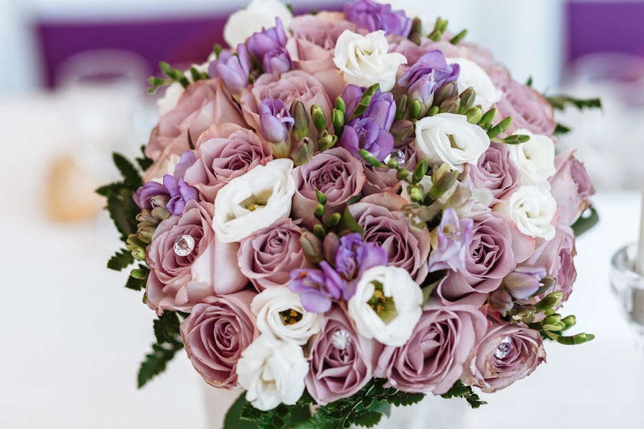 A close-up view of a floral arrangement featuring a bouquet of fresh flowers prepared by Bankside Flowers for a wedding. The bouquet includes soft pink roses, white lisianthus, and delicate purple fre
